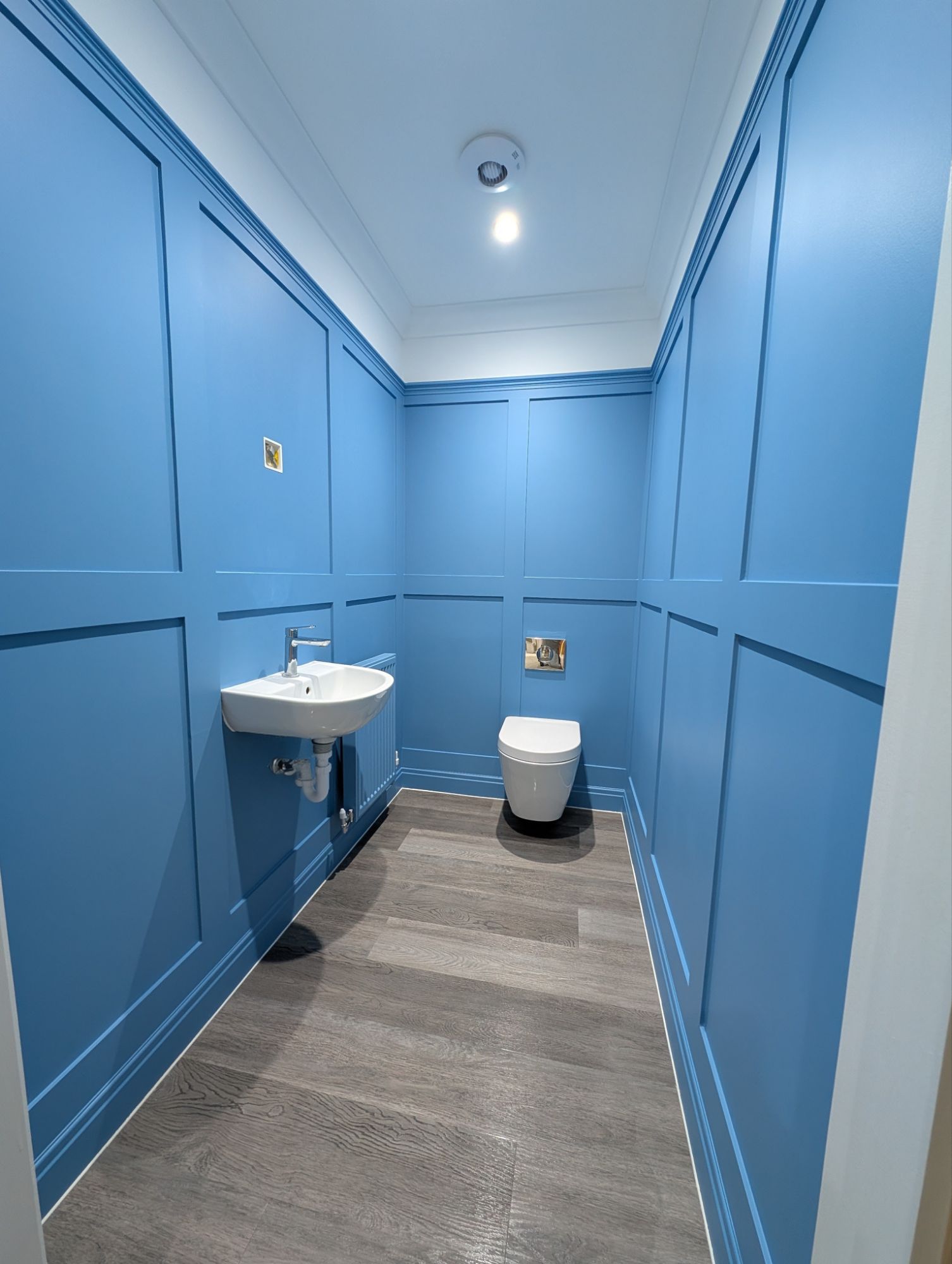 Blue wainscoting bathroom with wall panelling, sink and toilet, done by a decorator in Poole